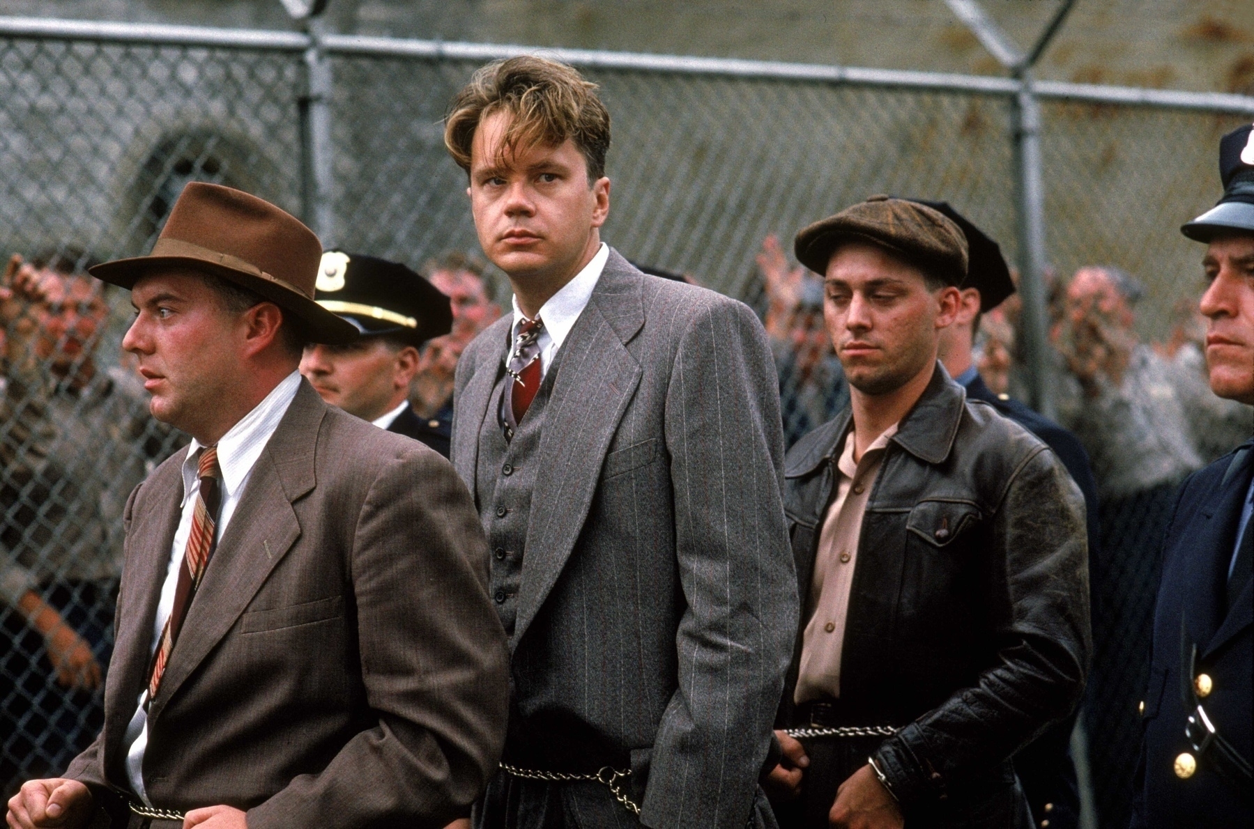 Movie still, The Shawshank Redemption: men walk in suits in line handcuffed. 