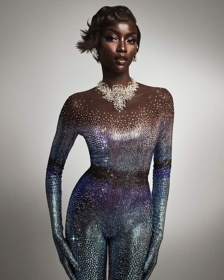 Beautiful women in a crystal studded skin-tight suit. She has dark skin and short hair. 