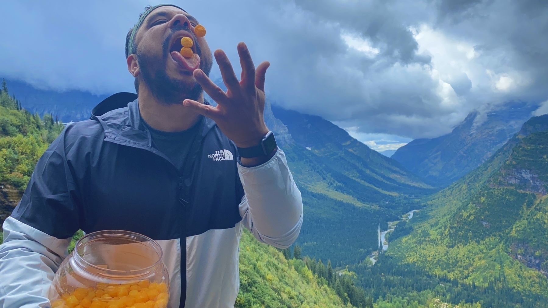 Me in Glacier National Park  eating cheeseballs with mountains behind me. 