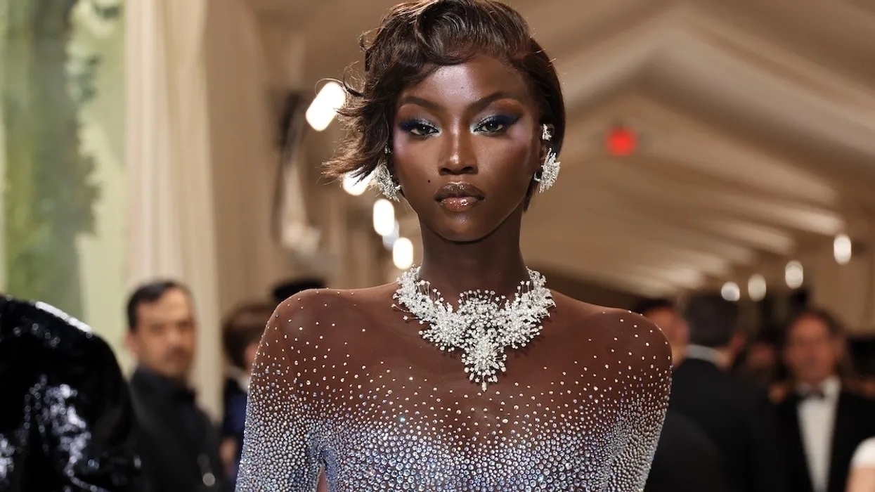 Beautiful women in a crystal studded skin-tight dress, looking at the camera. She has dark skin and short hair. 