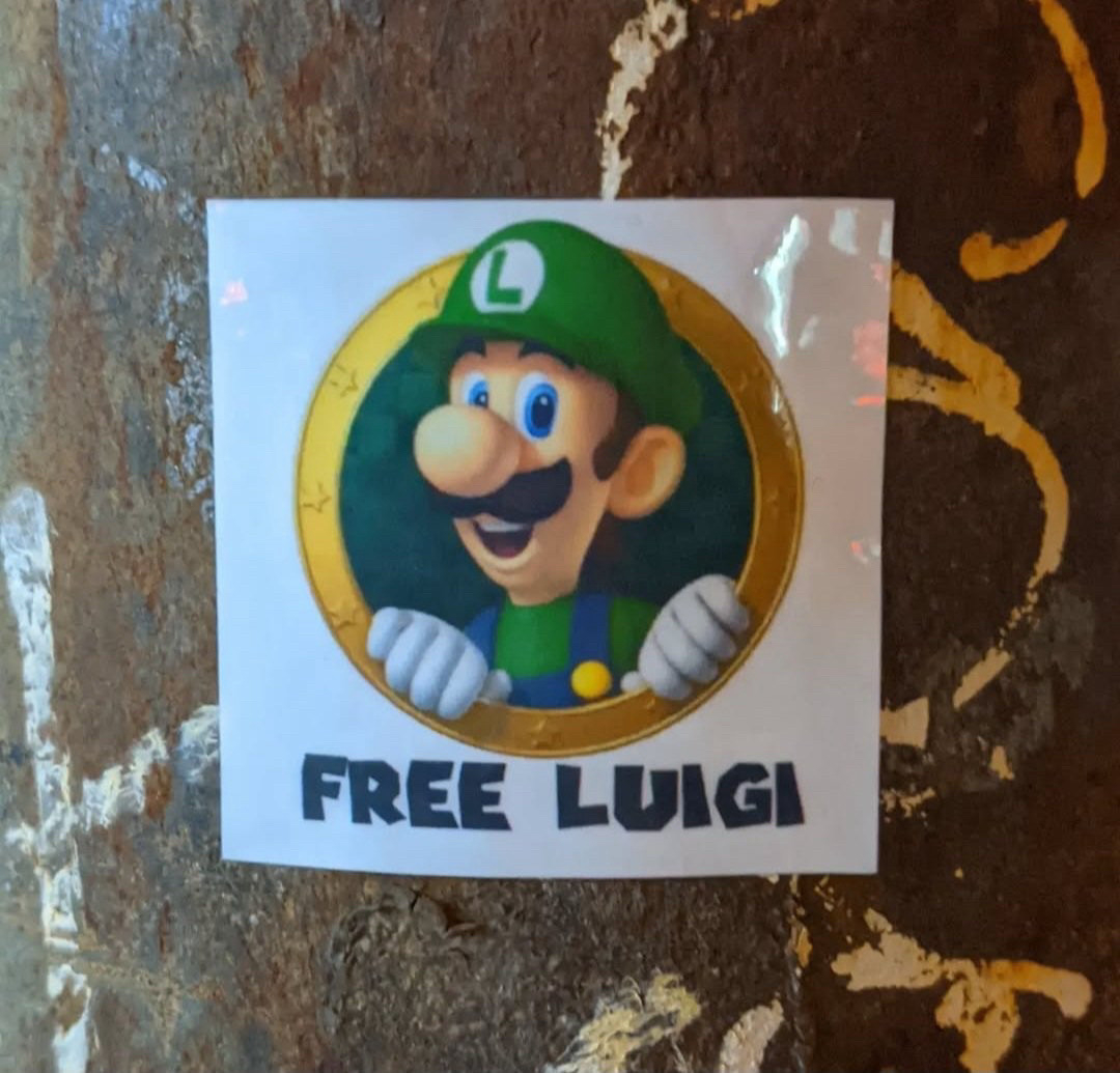 picture of a sticker on a pole of Luigi character that says free Luigi