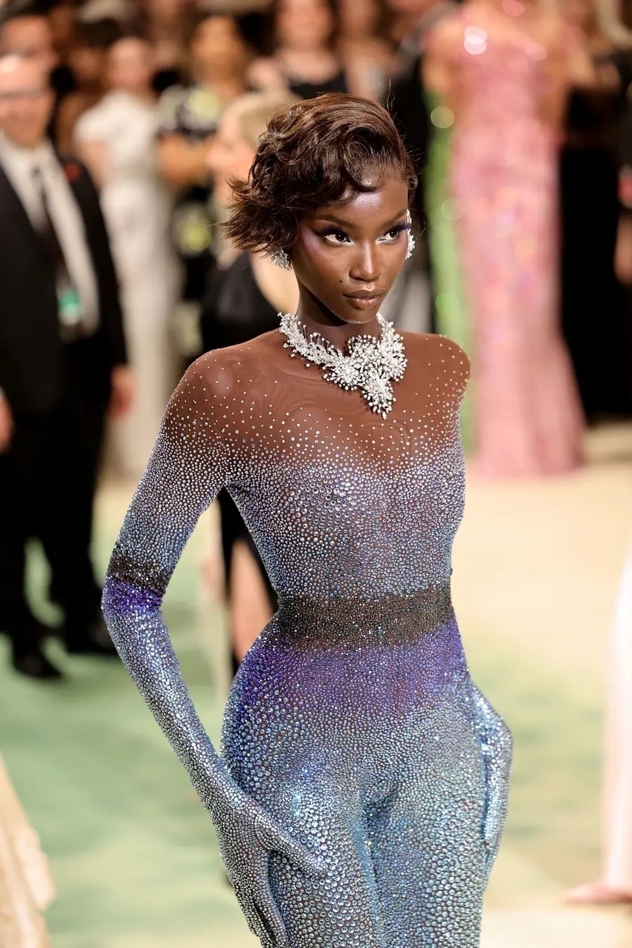 Beautiful women in a crystal studded skin-tight suit. She has dark skin and short hair. 