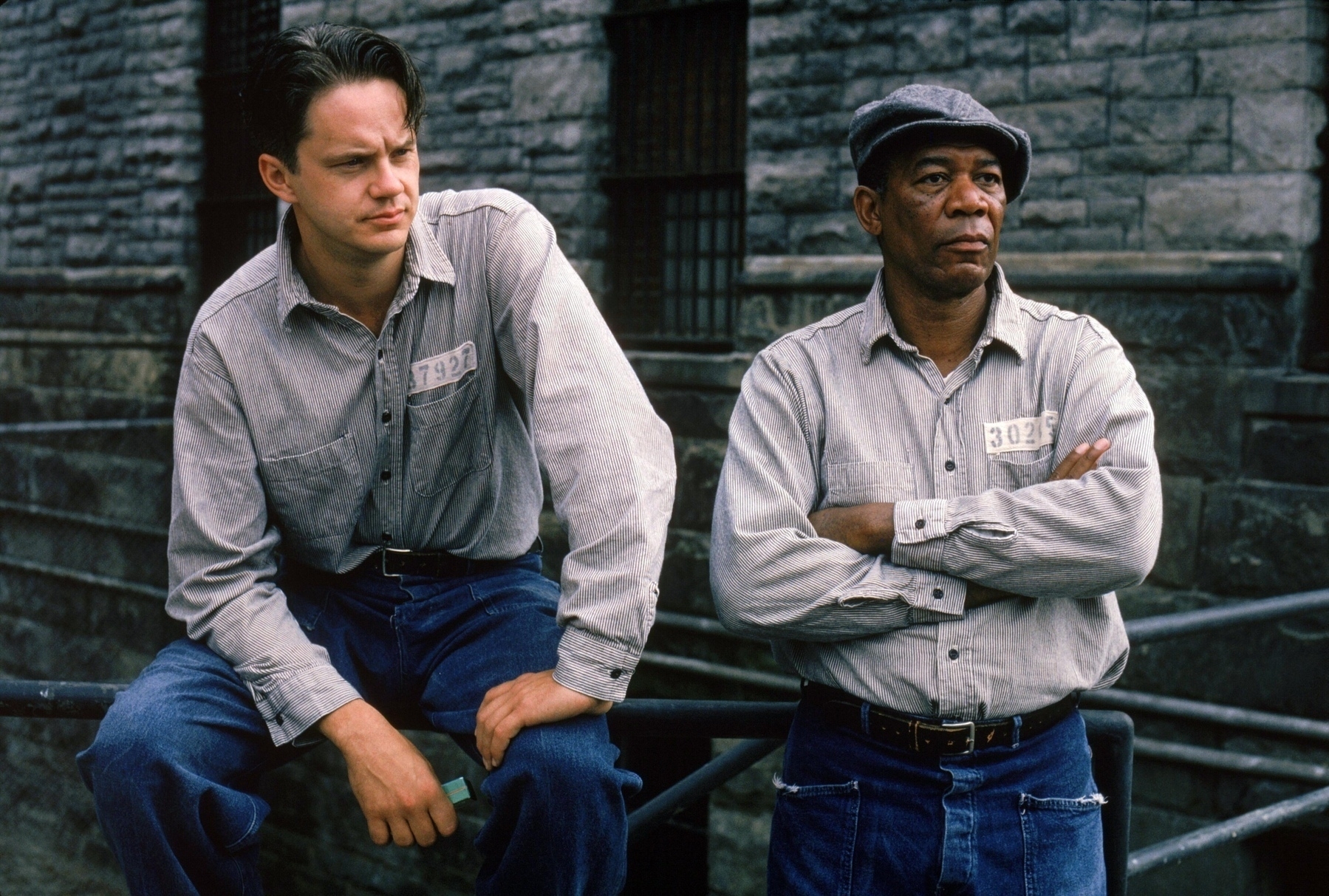 Two men, Andy and Red in prison cloths in the prison yard looking on. 