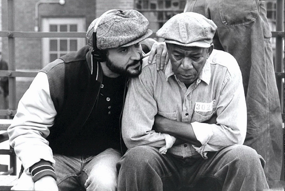 Movie still, The Shawshank Redemption: Man, presumably the director sits next to Morgan Freeman whispers in his ear. 