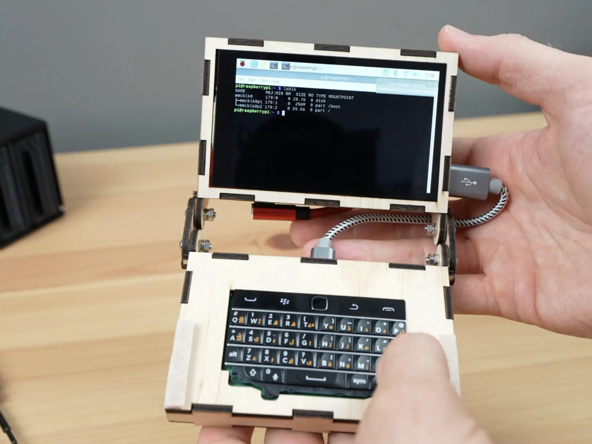 Tiny laptop computer fits in persons hand. 