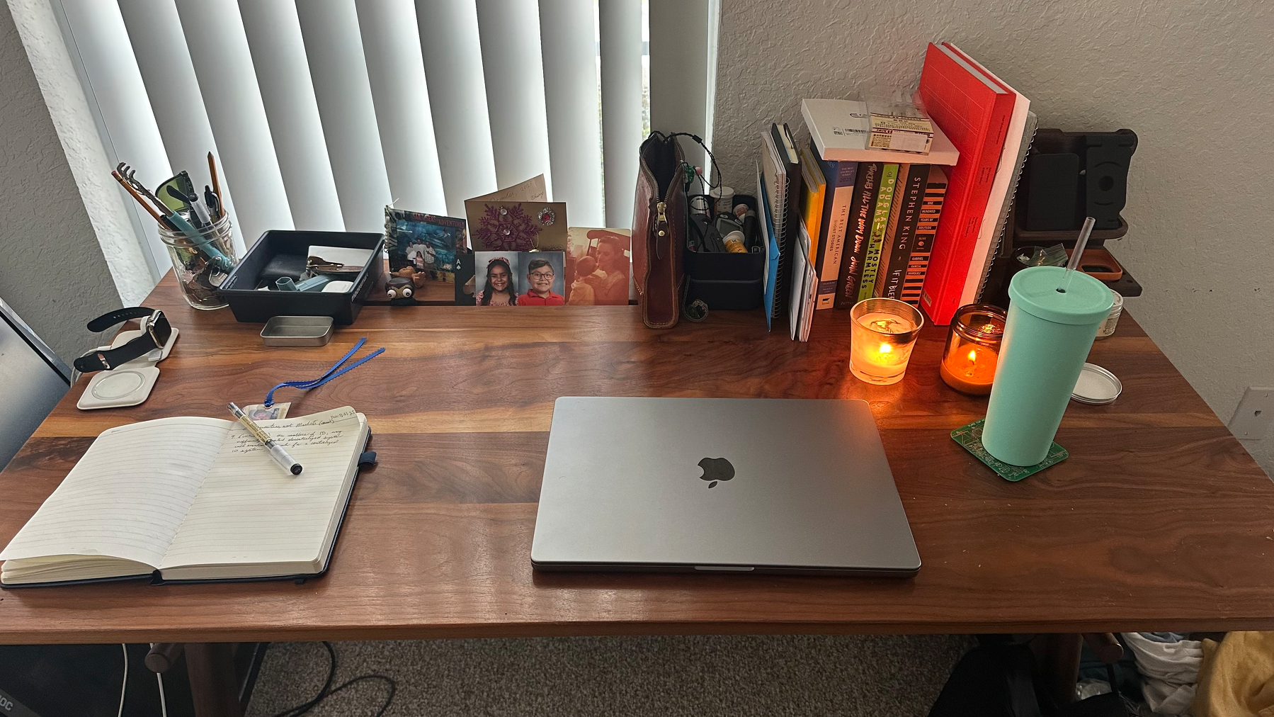 My cluttered desk with notebooks, books, drinks, candles, photos, a small doom box, etc on it. 