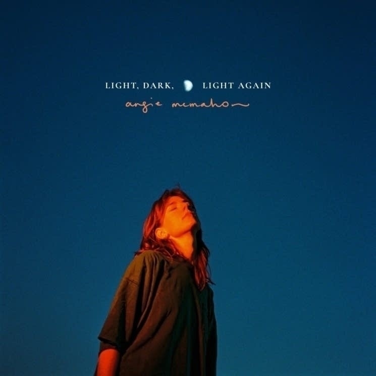 Album cover of woman in a large shirt looking up with her eyes closed. Dark blue gradient background. It reads: "Light Dark Light Again Angie McMahon."