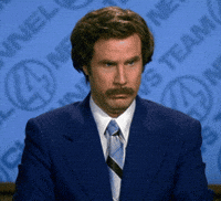 Ron Burgundy at his desk wearing a blue suit. He says "I don't believe you" then lights a cigarette.￼