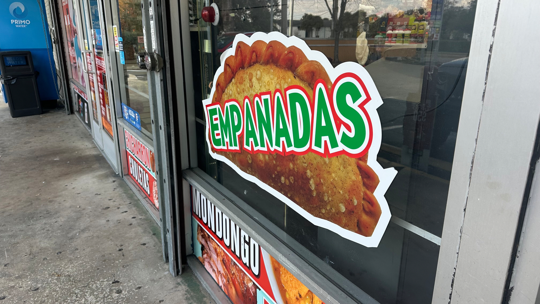 Window of a gas station with a graphic that reads "empanadas"